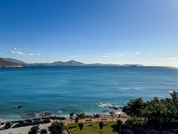 A breathtaking view of the sea in Varkiza, Greece, with clear blue waters and a rocky shoreline under a sunny sky