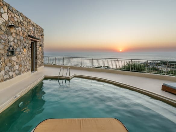 A serene view of a luxurious private pool at sunset, surrounded by lush greenery and overlooking the tranquil landscape of Livadia, Chania. The warm hues of the setting sun reflect on the pool’s shimmering surface, creating a peaceful and inviting ambiance that perfectly captures the essence of Mediterranean elegance.